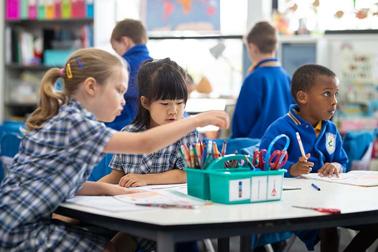 mixed race group of kids drawing and writing in class